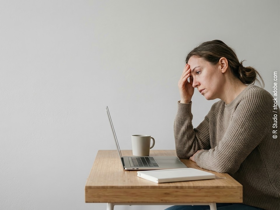 Mitarbeiterin sitzt allein am Laptop im Homeoffice, Sinnbild für soziale Isolation im mobilen Arbeiten